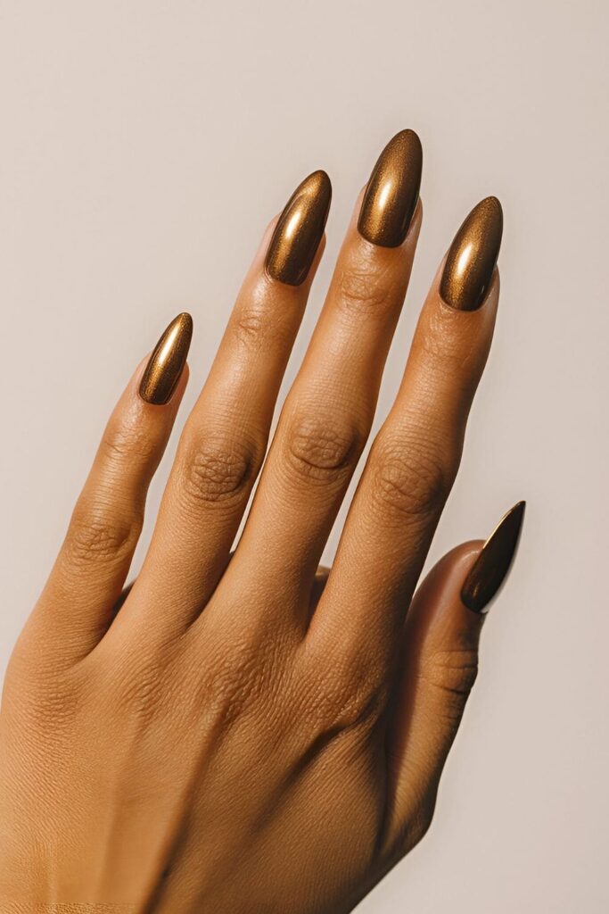 A hand featuring dark topaz acrylic nails with a deep, brownish-gold hue, warm and glamorous, perfect for evening events