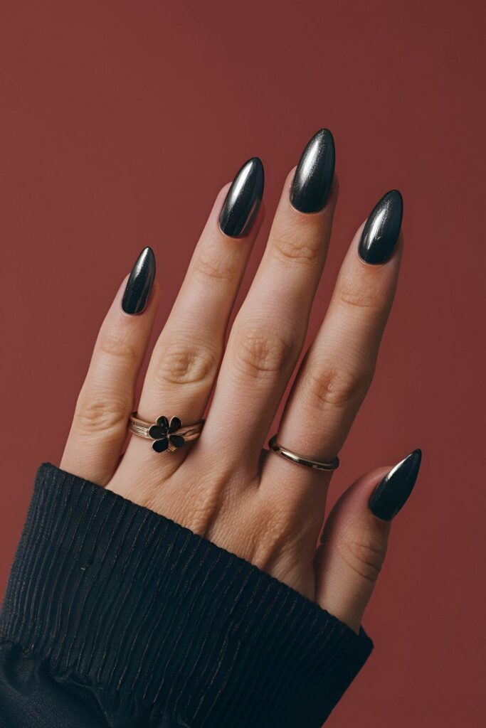 A hand featuring gunmetal acrylic nails with a dark, metallic finish, edgy and chic, adding glamour to any outfit