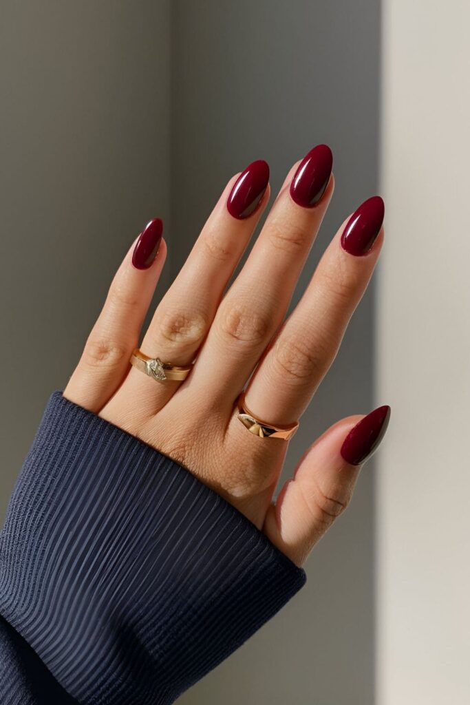 A hand featuring rich burgundy acrylic nails, exuding a classic, warm hue perfect for making a statement on summer evenings