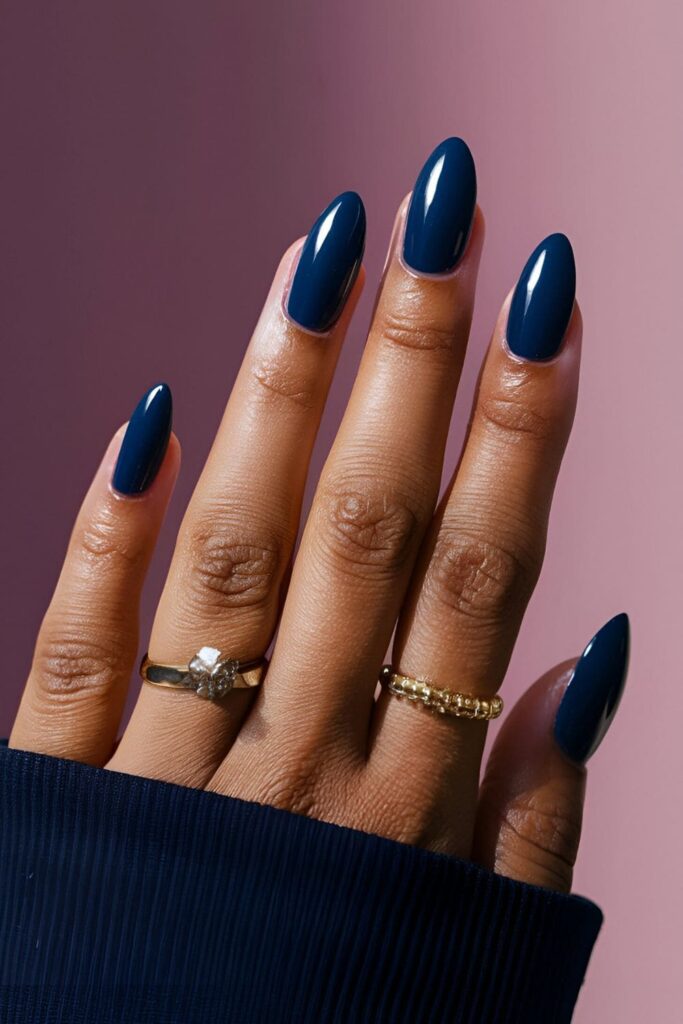 A hand showcasing deep navy blue acrylic nails with a glossy top coat, reflecting light for a sophisticated and stylish look