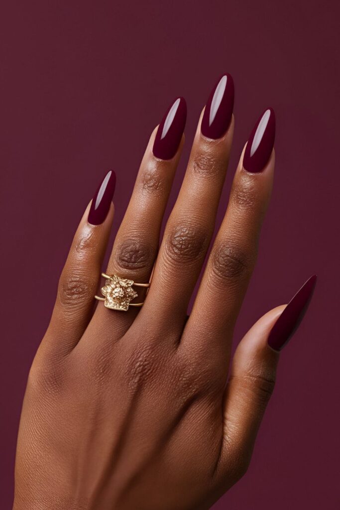 A hand showcasing deep, rich wine red acrylic nails, elegant and timeless, exuding a sense of royalty and sophistication