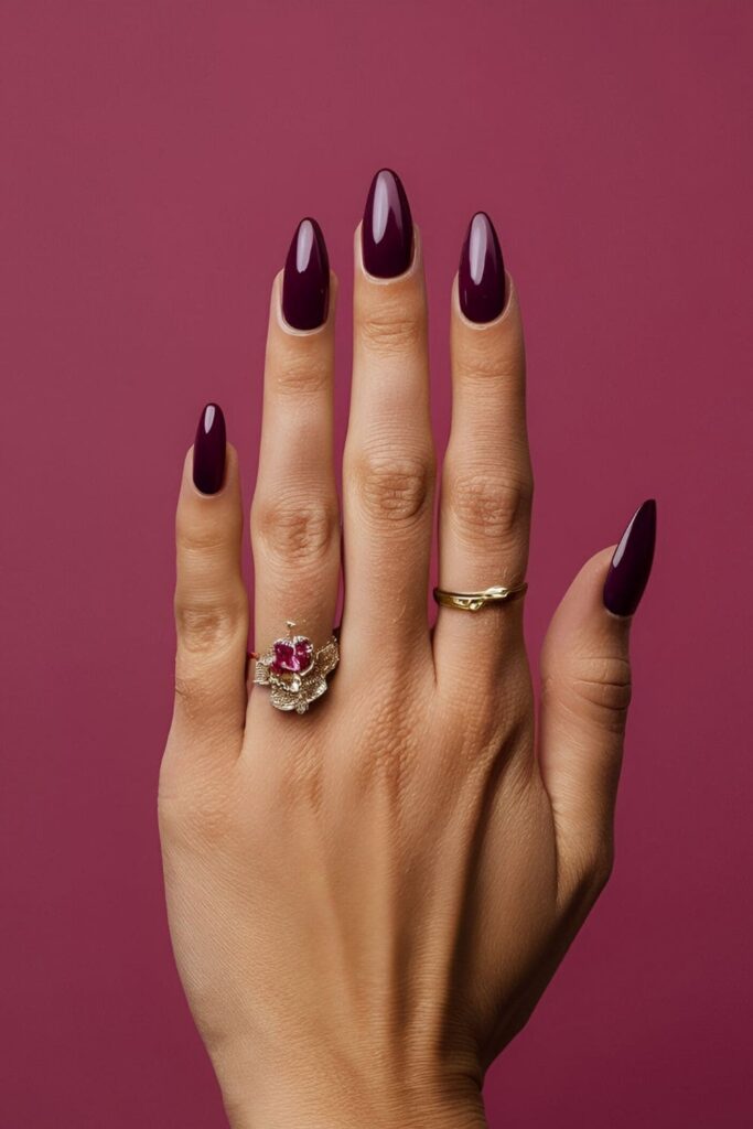 A hand showcasing rich, dark purple-red mulberry acrylic nails, unique and sophisticated, ideal for adding luxury to a summer look