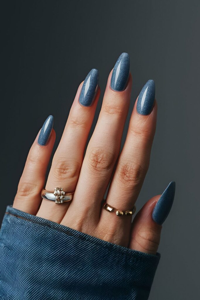 A hand showing slate blue acrylic nails with gray undertones, subtle and stylish, possibly with a denim effect