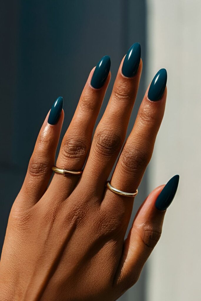 A hand with rich, dark blue-green acrylic nails, bold and beautiful, perfect for standing out on beach days and summer nights