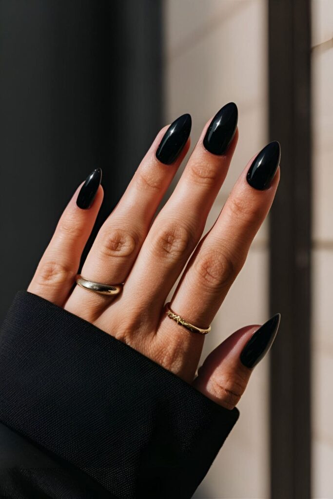 A hand with sleek, polished midnight black acrylic nails, featuring a glossy finish, versatile for casual and formal attire