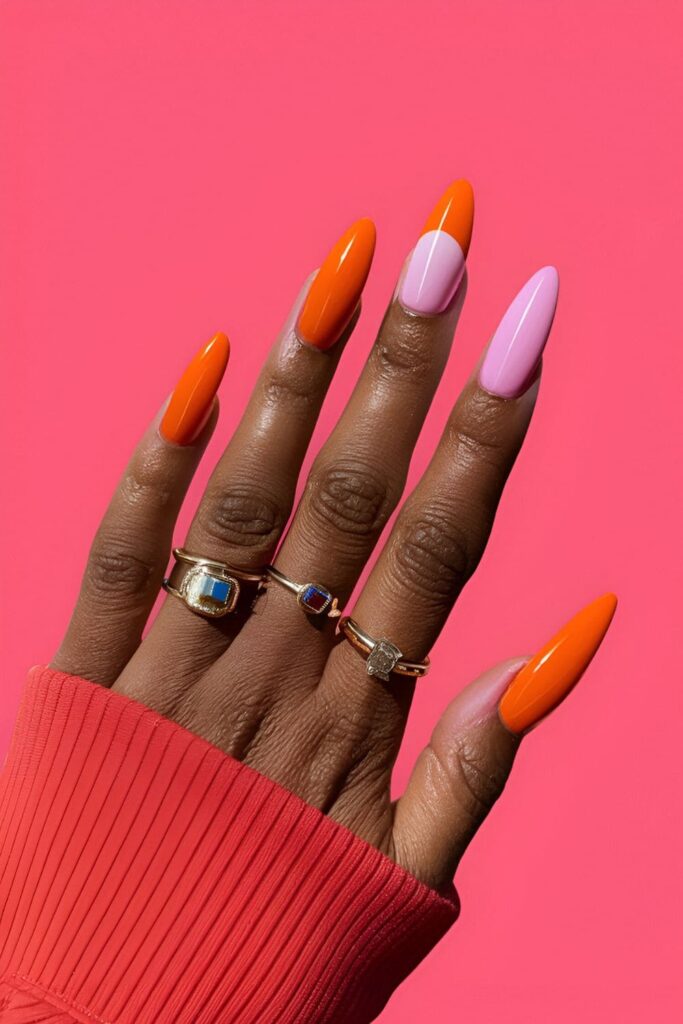 Acrylic nails blending vibrant orange and playful pink, featuring ombre effects and geometric patterns