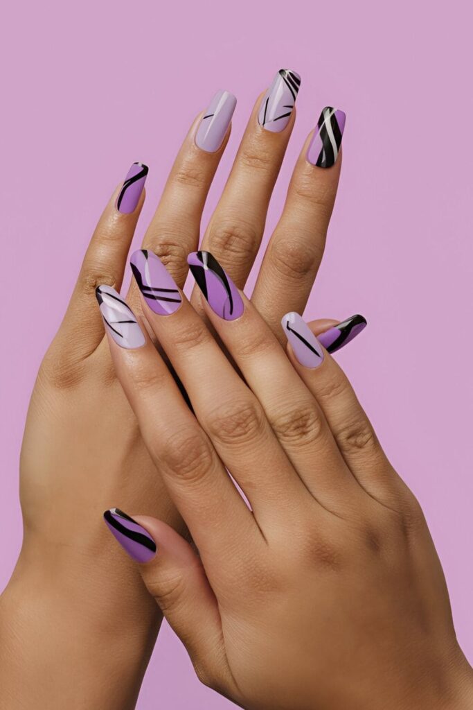 Acrylic nails featuring abstract art in various shades of purple, with random shapes and contrasting black and white lines