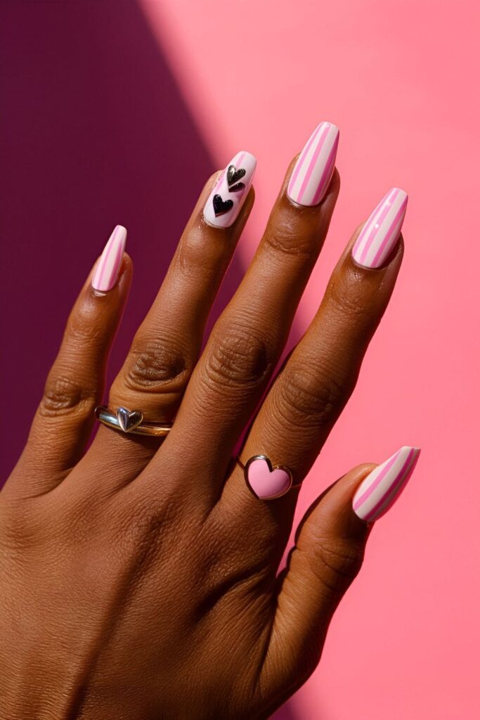 Acrylic nails featuring pink stripes and heart designs, adding a playful touch and designed for dark skin tones