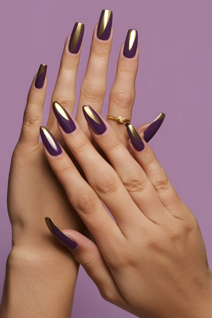 Acrylic nails painted in a deep royal purple shade with gold accents, exuding luxury and sophistication