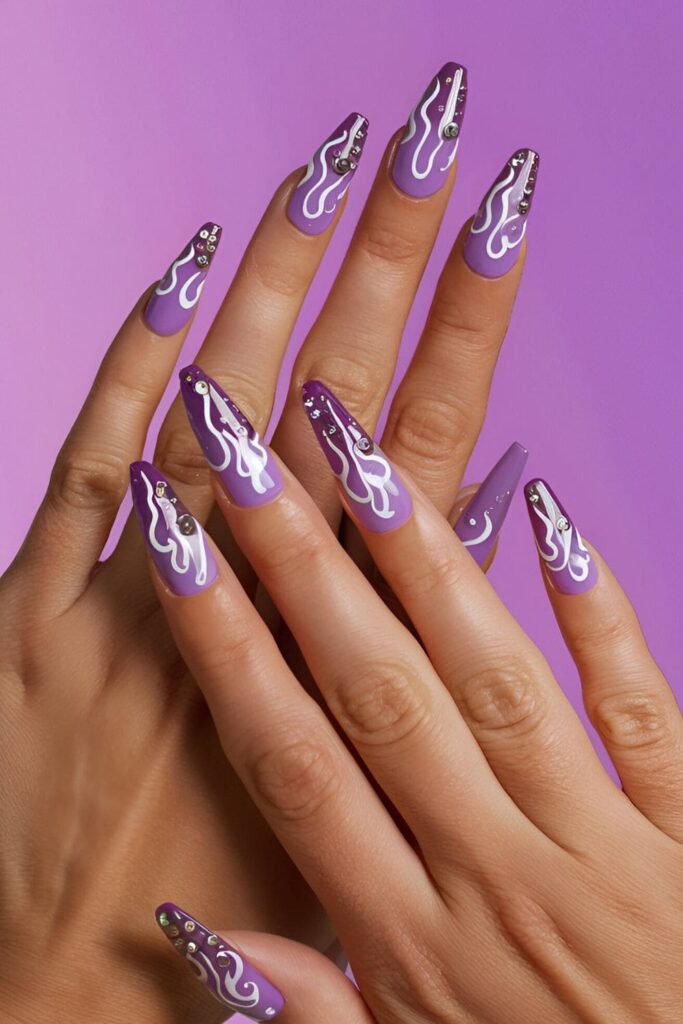 Acrylic nails with a purple base, featuring flame designs in white or black, and embellished with rhinestones for extra sparkle