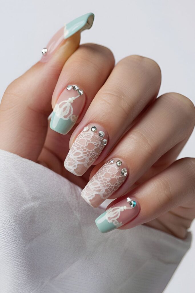 Acrylic nails with light bases, delicate lace patterns, and rhinestones accentuating the design