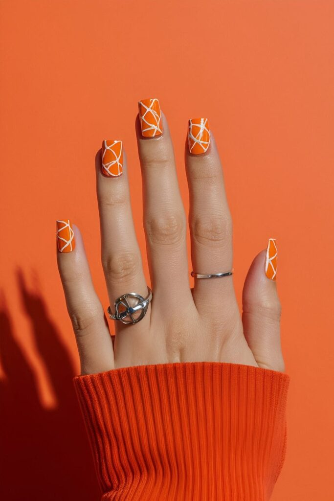 Acrylic nails with tiny orange slices on a vibrant orange base, fun and fresh fruit-inspired nail art