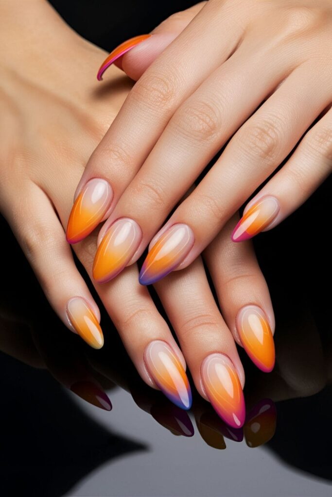 Almond nails with a gradient that blends warm colors like orange, pink, and purple from the base to the tips