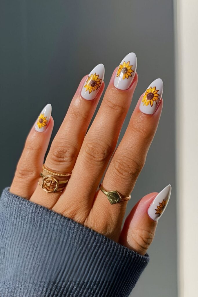 Almond nails with a yellow base and detailed sunflower designs with brown centers