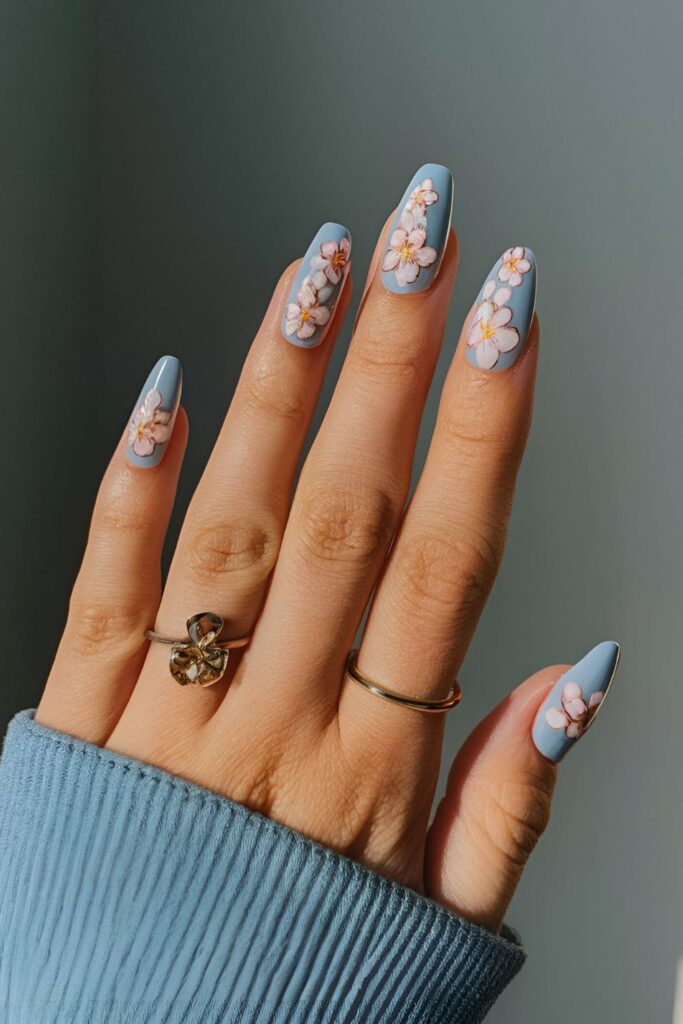 Baby blue base nails with detailed pink and white cherry blossoms, creating a serene and beautiful look