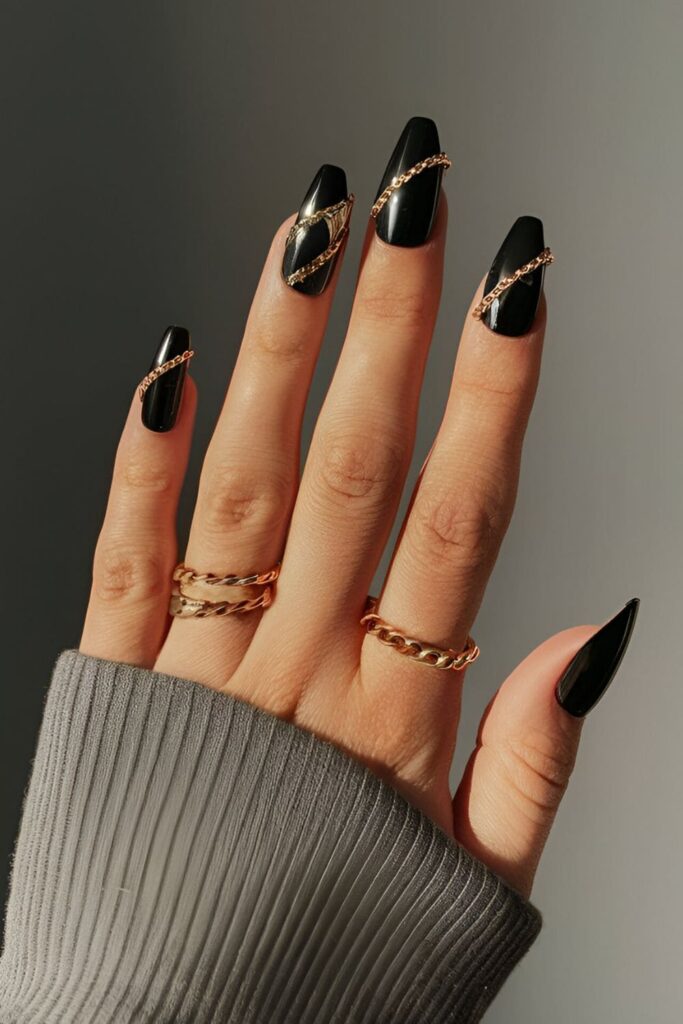 Black acrylic nails accented with gold chains, adding a touch of luxury and boldness