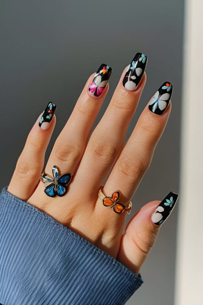 Black acrylic nails adorned with colorful butterfly designs, adding a feminine and whimsical touch