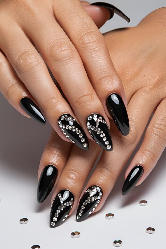 Black acrylic nails adorned with sparkling rhinestones, arranged in elegant patterns for added glamour