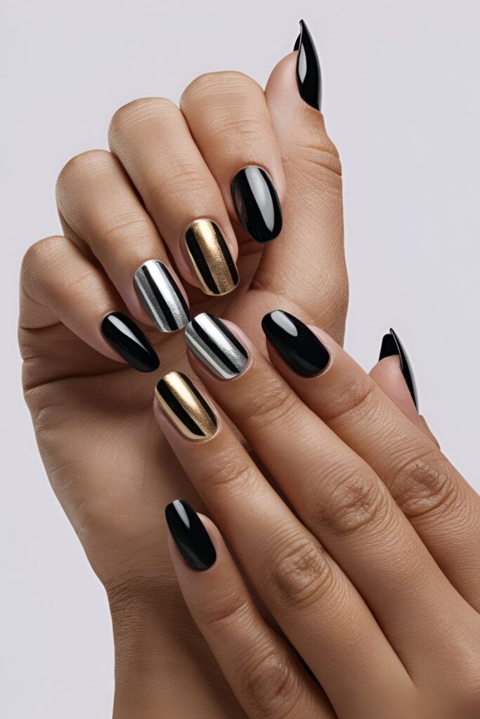 Black acrylic nails featuring bold metallic accents in gold and silver, creating a striking look