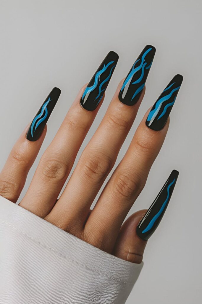 Black acrylic nails featuring bright blue flame designs, perfect for an edgy and eye-catching look