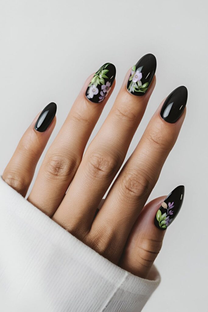 Black acrylic nails featuring bright floral designs in purple and green, offering a beautiful summer contrast