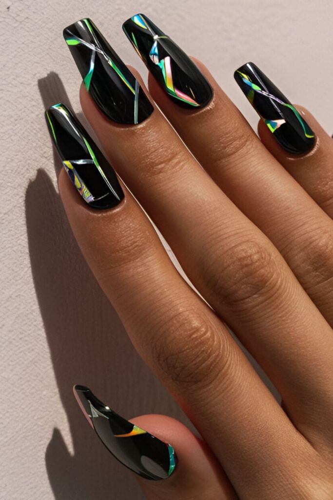 Black acrylic nails with a bold shattered glass effect using iridescent pieces, creating a futuristic style