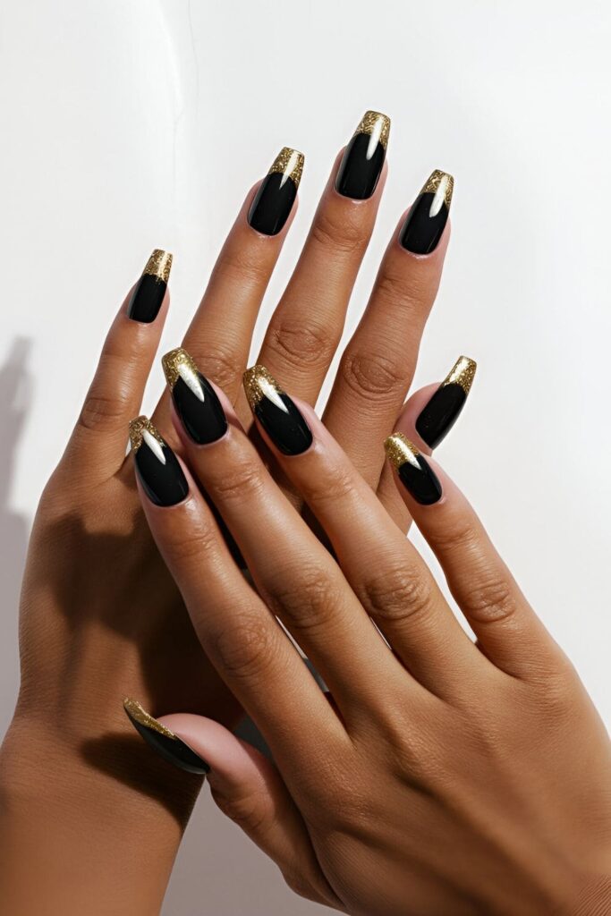 Black acrylic nails with shimmering gold glitter tips, perfect for a glamorous summer look