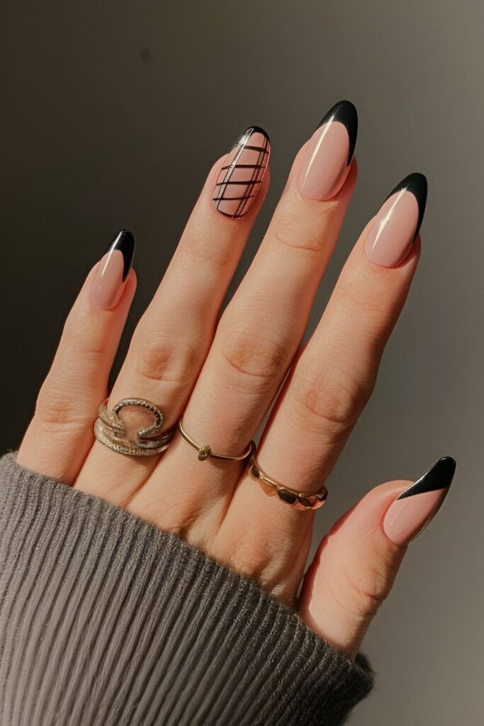 Black and nude acrylic nails, with black tips and patterns on a nude base for a balanced, elegant appearance