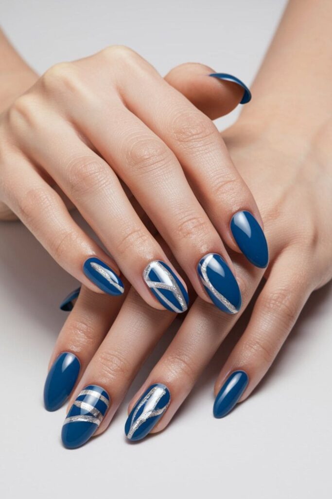 Blue acrylic nails featuring silver foil accents in abstract designs