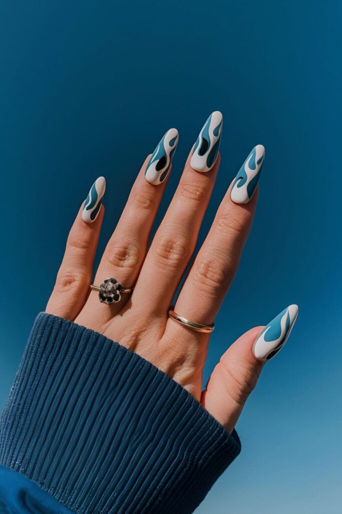 Blue acrylic nails with contrasting white or black flame designs