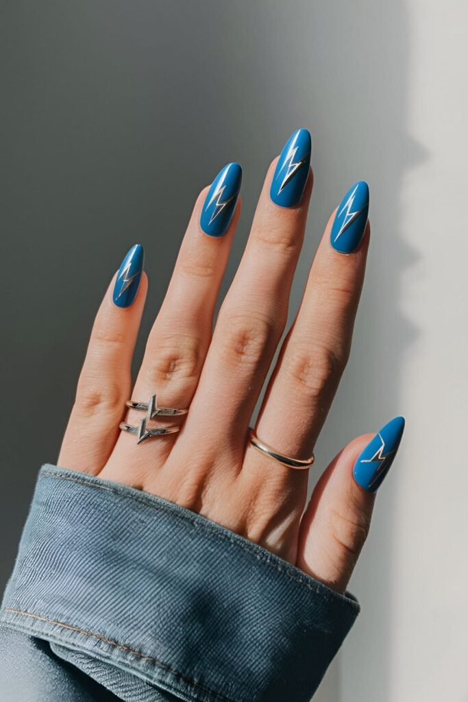 Bold blue acrylic nails featuring silver lightning bolt patterns