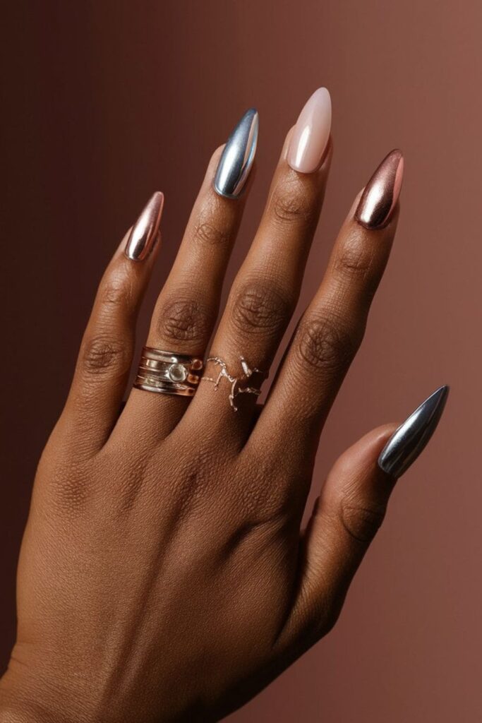 Dark-skinned hands with silver, chrome, and rose gold acrylic nails, featuring ombre effects