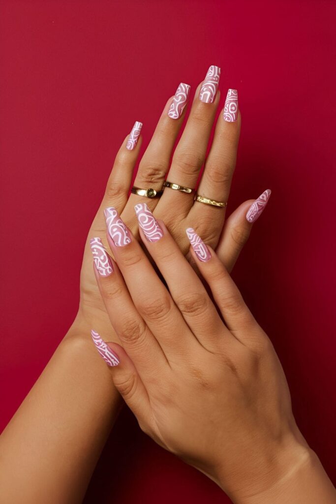 Bold pink acrylic nails with intricate white tribal pattern designs