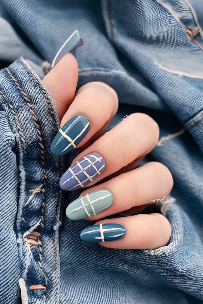 Casual acrylic nails in shades of blue with white stitching mimicking denim fabric, positioned against a relaxed, laid-back background