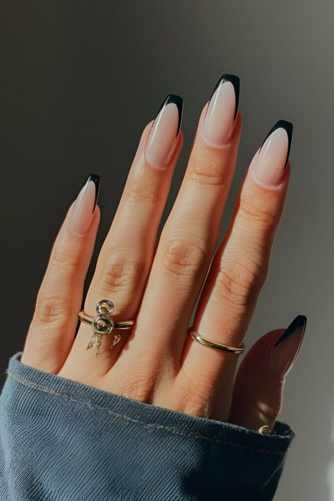 Clear or nude base nails with sleek black French tips, a modern twist on the classic French manicure