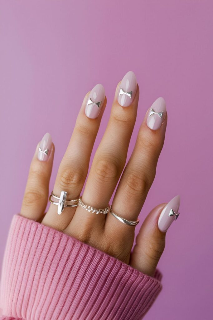 Cute and feminine nails with small silver bow designs on a clear or colored base for a playful look