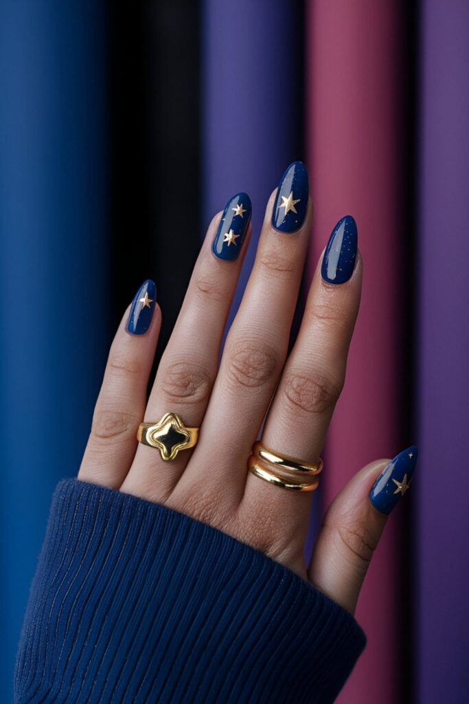 Deep blue and purple nails with gold accents, including star and moon decals for a cosmic look