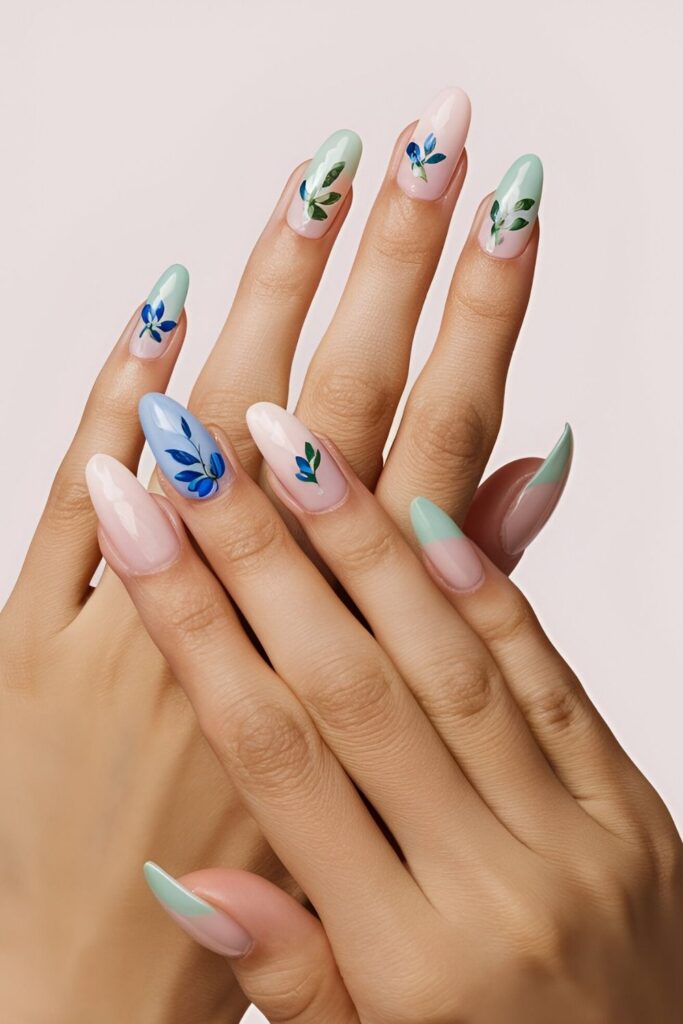 Feminine-nails-with-delicate-blue-flowers-painted-on-a-light-pink-or-light-green-base-accented-with-green-leaves