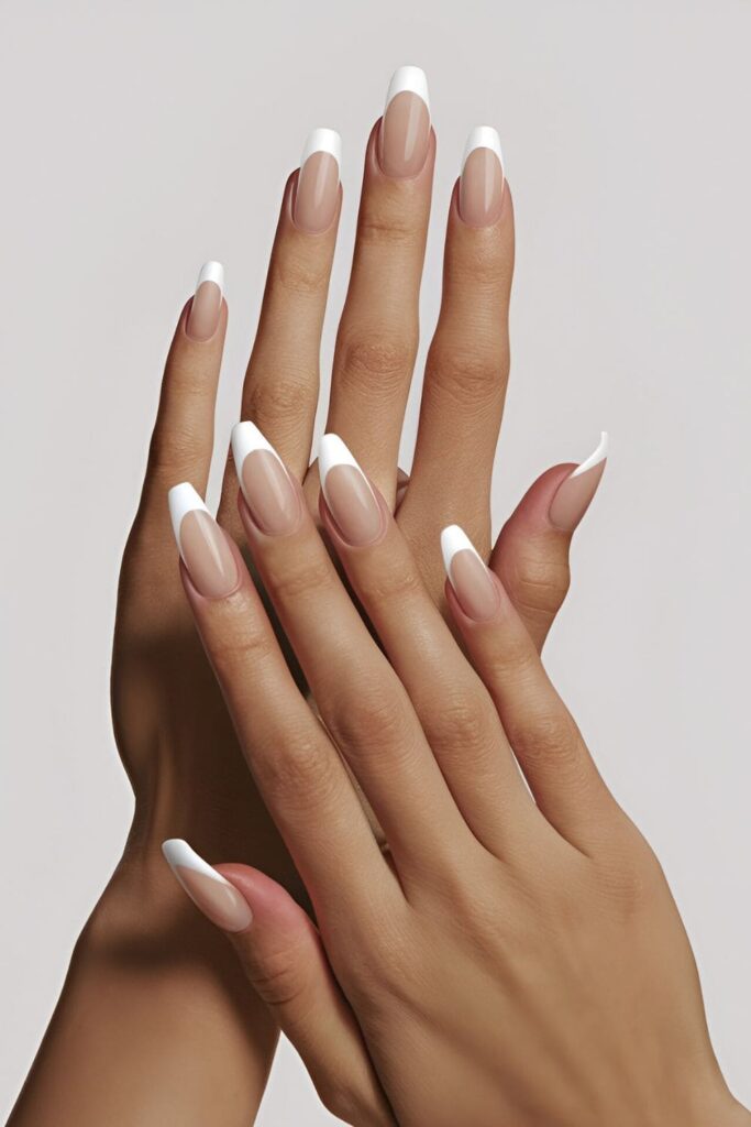 Image of hands with acrylic nails featuring a natural-looking base and white tips, showcasing a clean and polished appearance