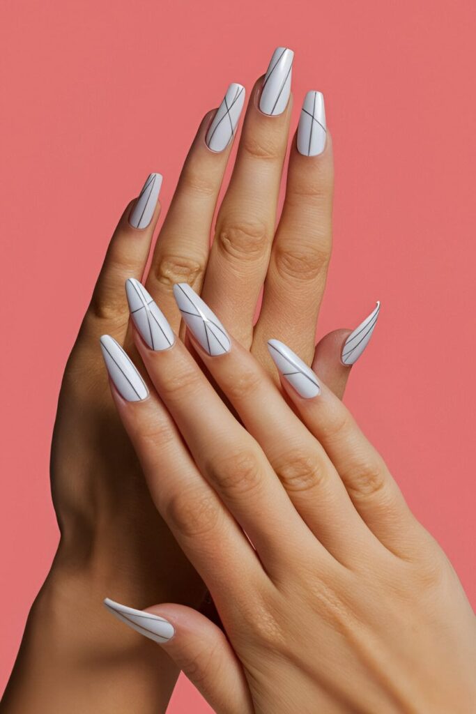 Image of hands with acrylic nails featuring a white base and thin silver lines, creating a clean and polished appearance with a touch of elegance