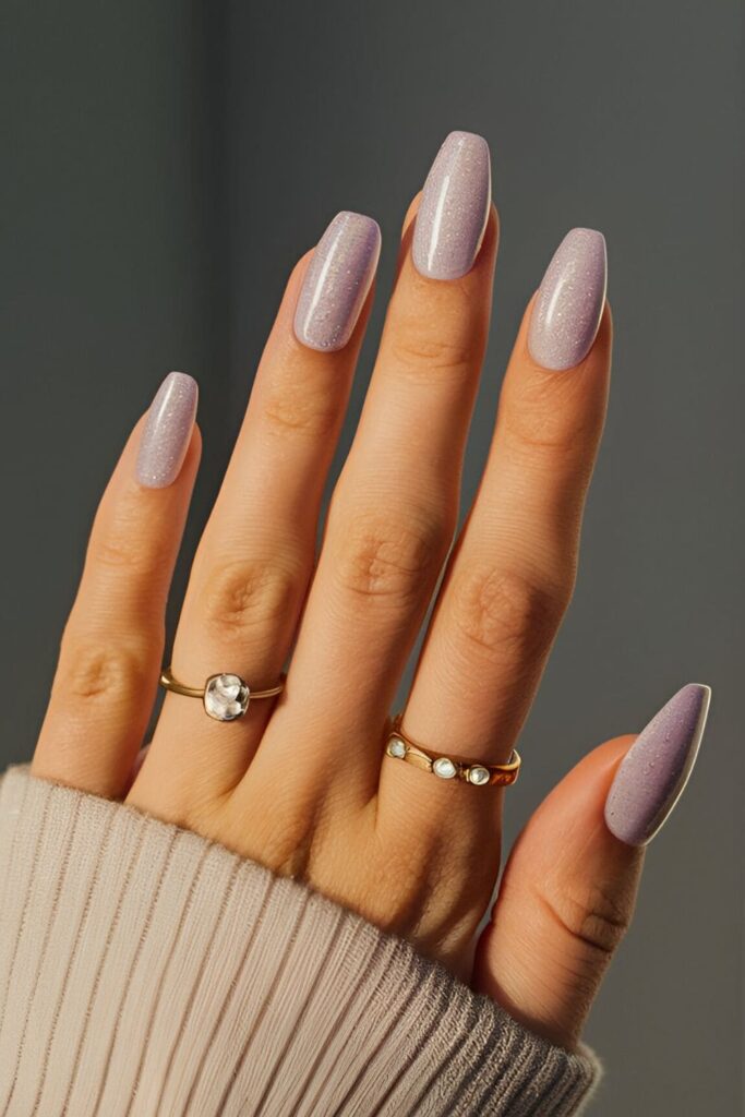 Image of hands with acrylic nails in a light lavender base with fine glitter, providing a soft look with a subtle shimmer that adds a bit of sparkle without being overpowering