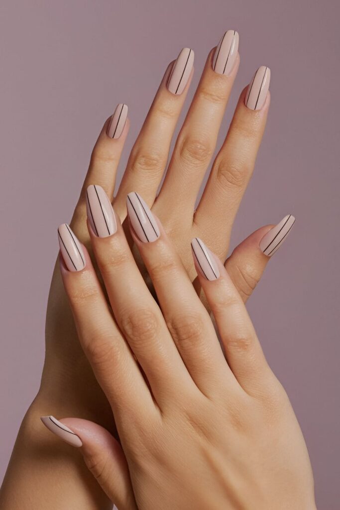 Image of hands with acrylic nails in a nude base with thin vertical, horizontal, or diagonal lines in black or other neutral colors, emphasizing a sleek and modern look