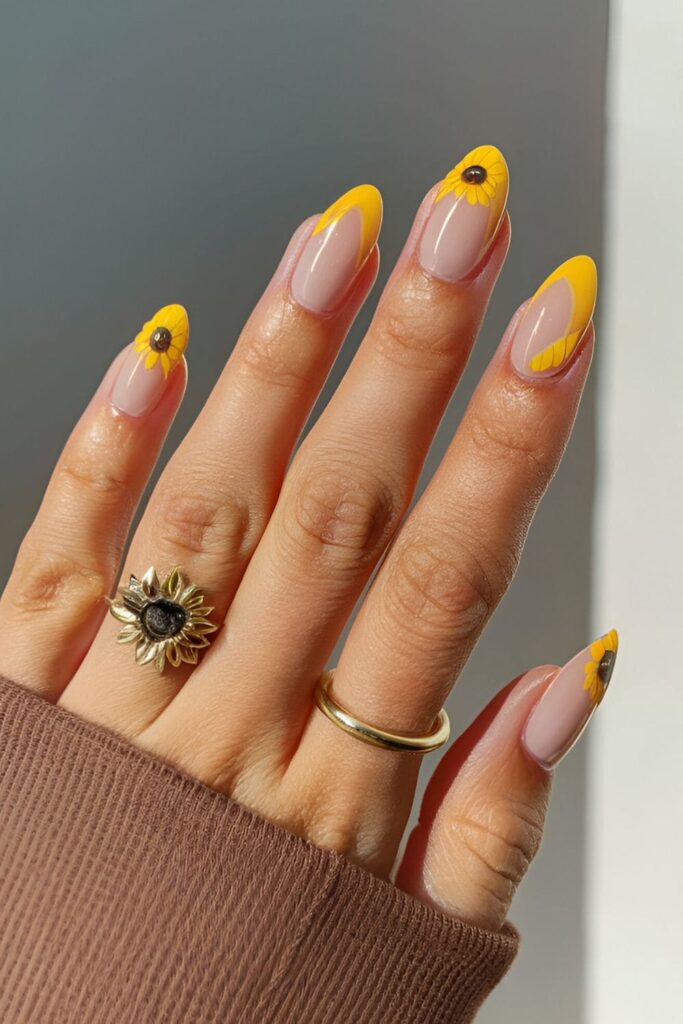 Light brown or nude base nails featuring vibrant yellow sunflowers with dark centers