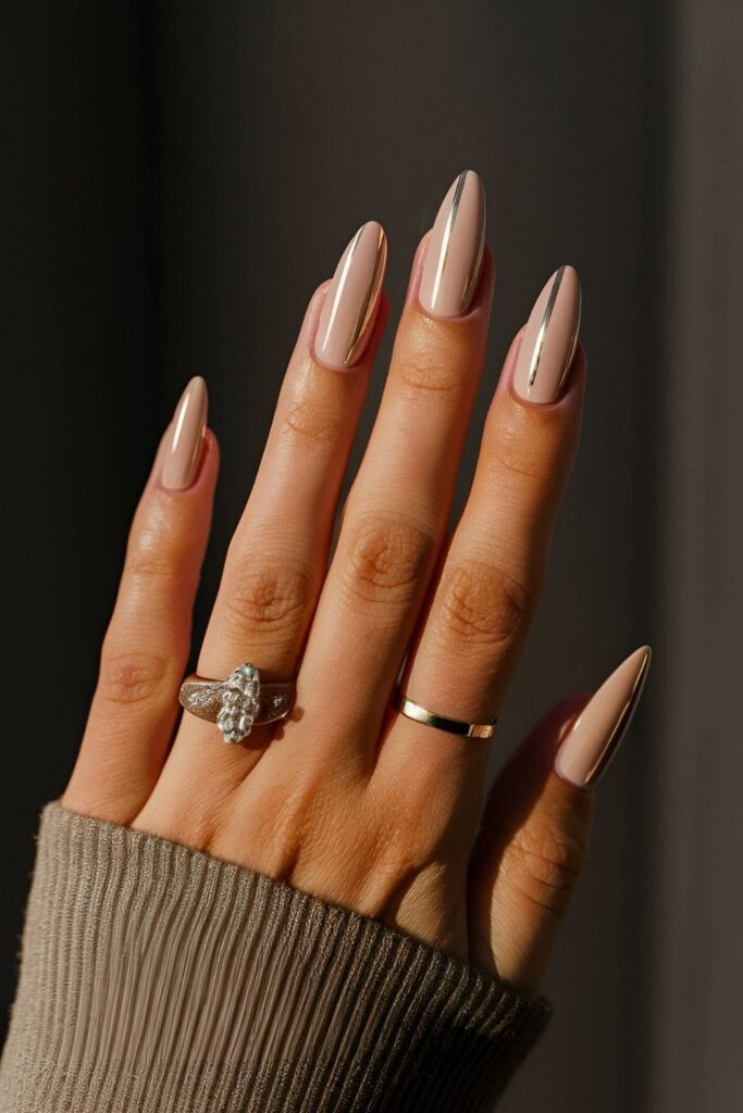 Manicure with a nude base and thin metallic lines in gold, creating a sleek and modern look