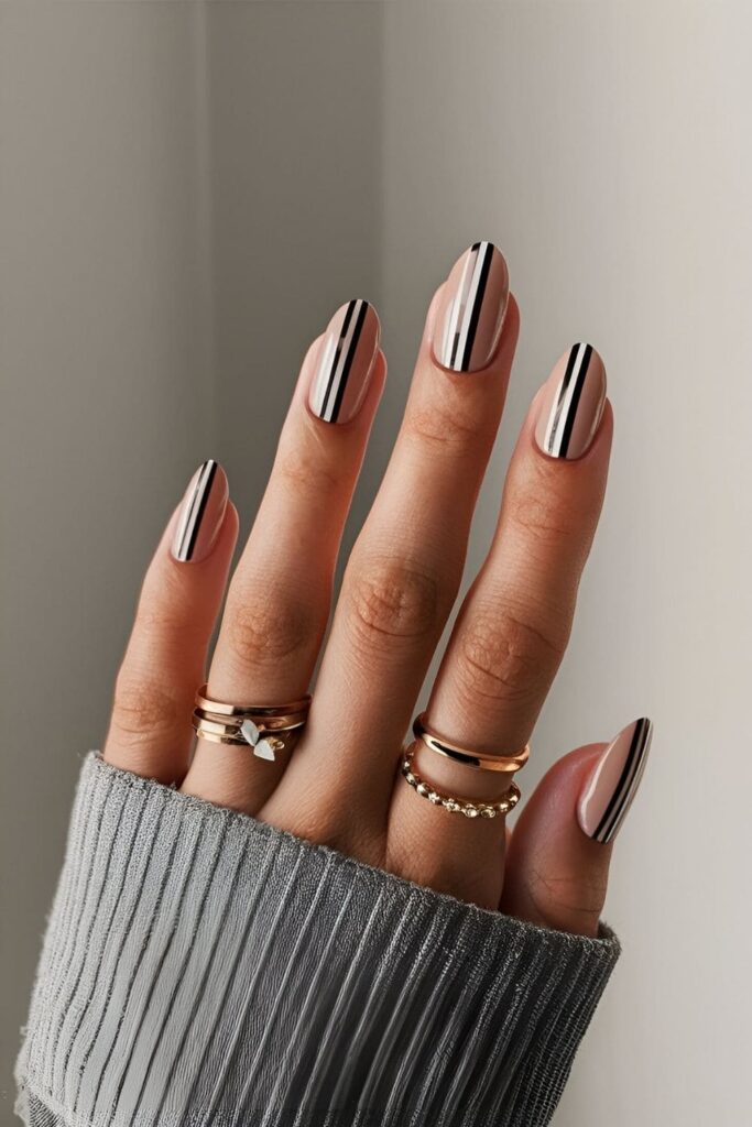 Manicure with a nude base and thin vertical or horizontal bars in black, white, or metallic shades for a modern design