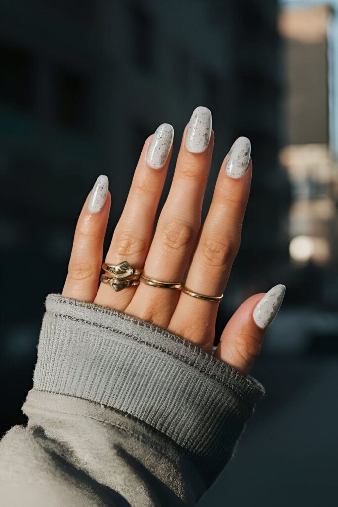 Matte white nails with subtle silver glitter, creating a frosted, winter wonderland effect