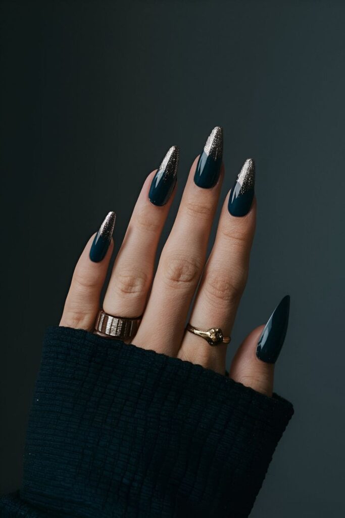 Moody dark nails with deep blue or black base and metallic or glitter accents