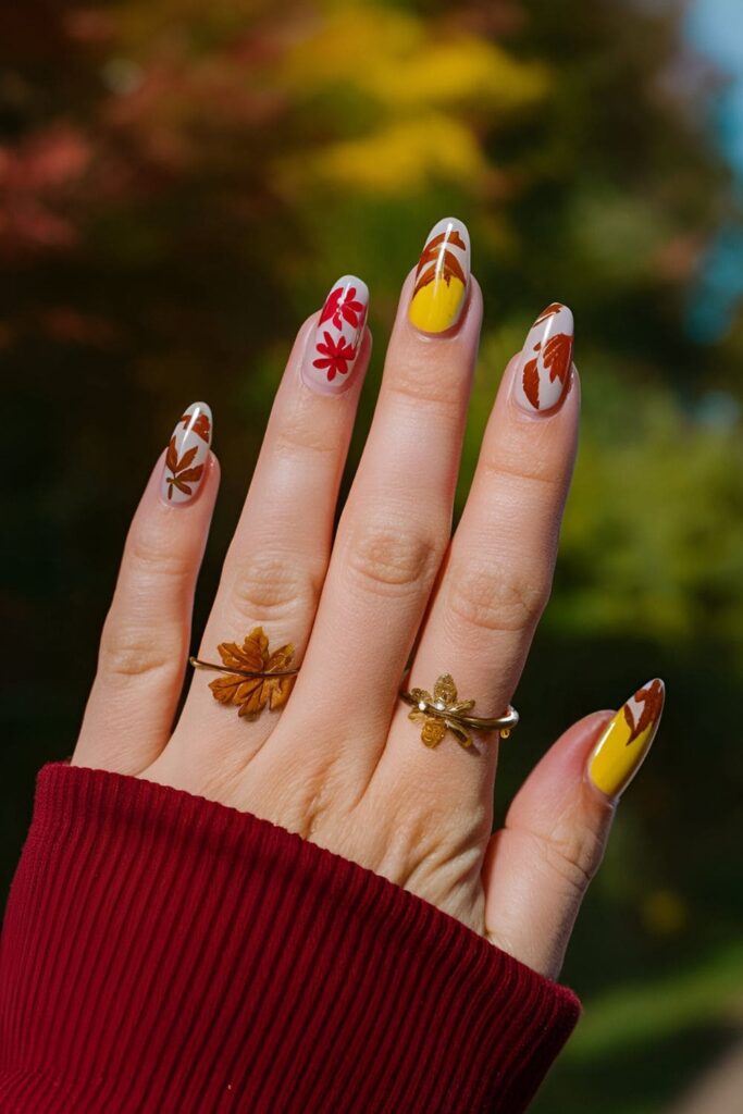 Nails decorated with red, yellow, and brown autumn leaf designs, seasonal and nature-inspired nail art