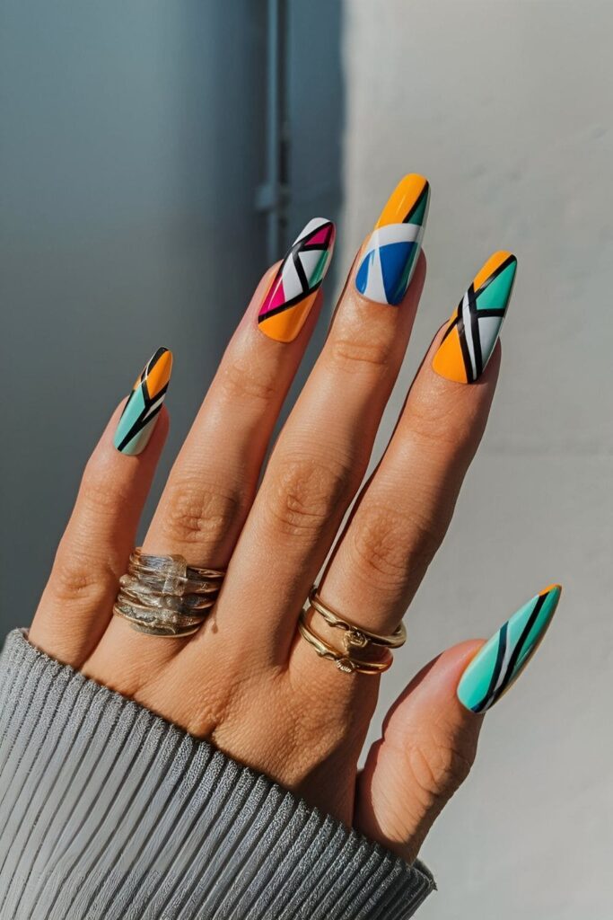 Nails featuring bold geometric patterns with sharp lines, triangles, and abstract shapes in bright, contrasting colors