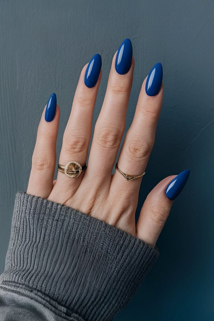 Nails painted in a rich royal blue color, adding a bold and elegant look with a dramatic and high-class element